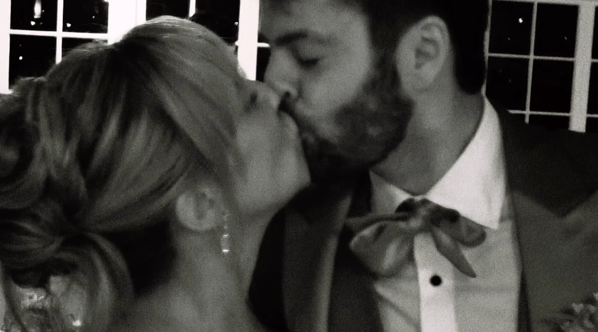 Black and white photo of a couple kissing at what appears to be a formal event or wedding, with the man wearing a tuxedo with bow tie